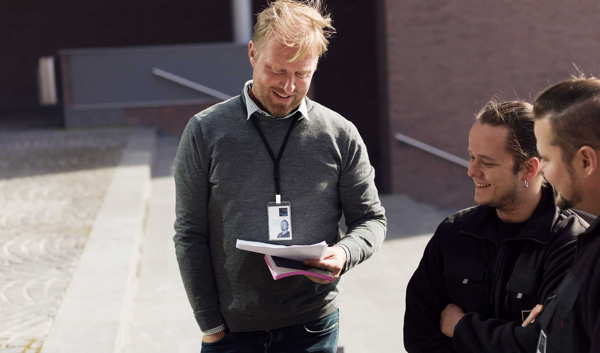 Three men standing and going through papers