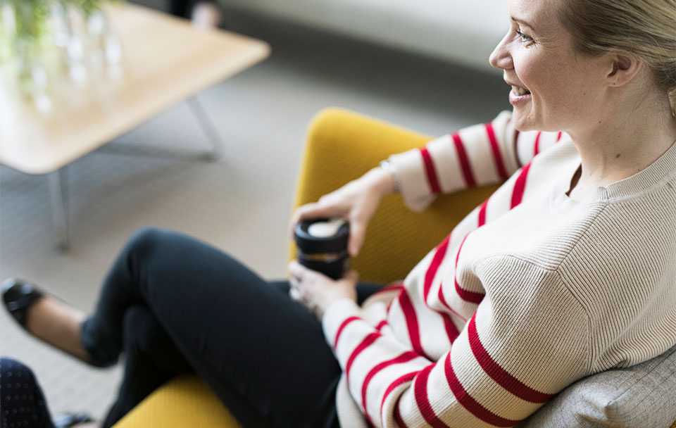 A woman sitting on a sofa with a cup of coffee